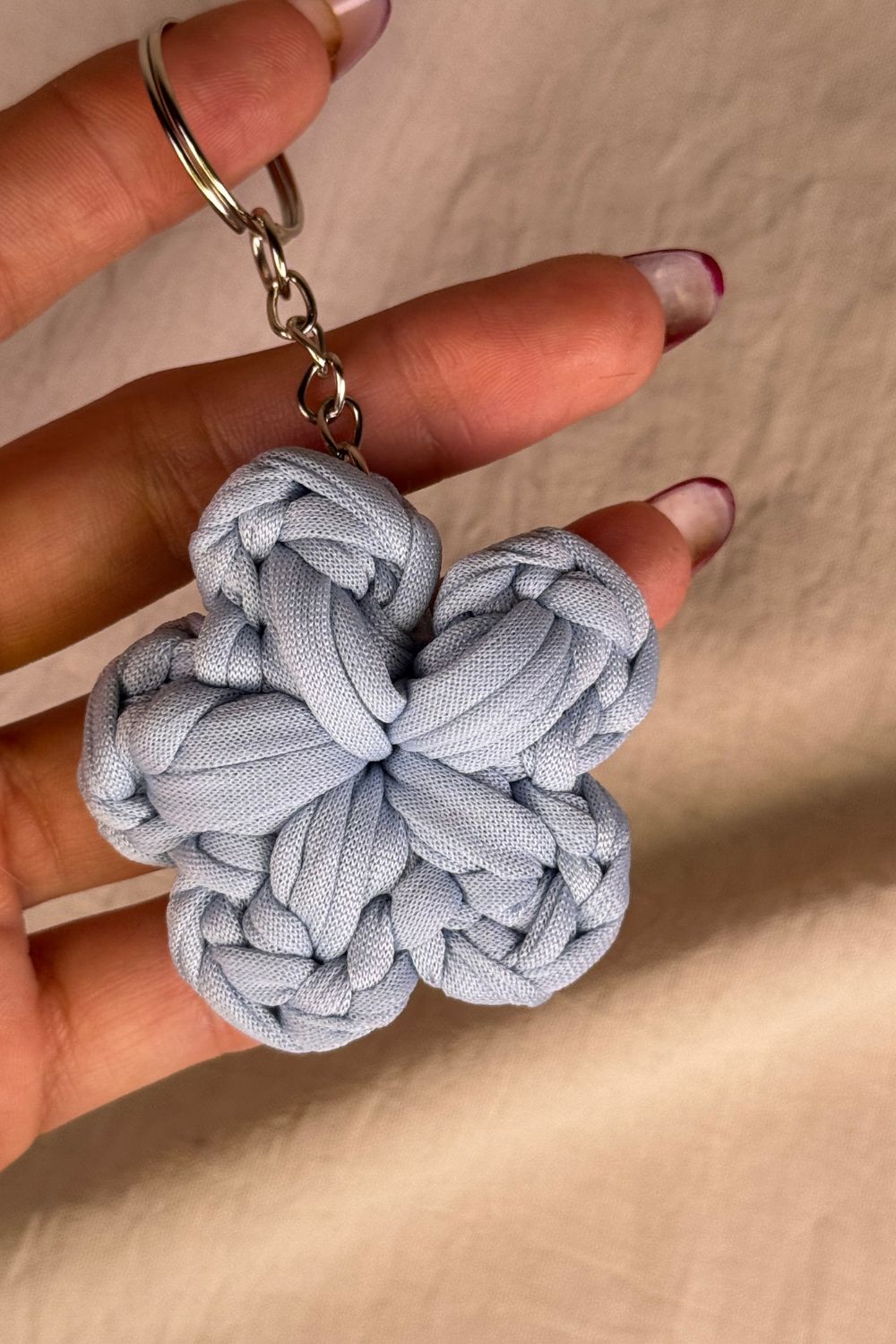 Dettaglio ravvicinato del portachiavi fiore azzurro Made By Hand, che mostra la lavorazione all’uncinetto e la texture artigianale