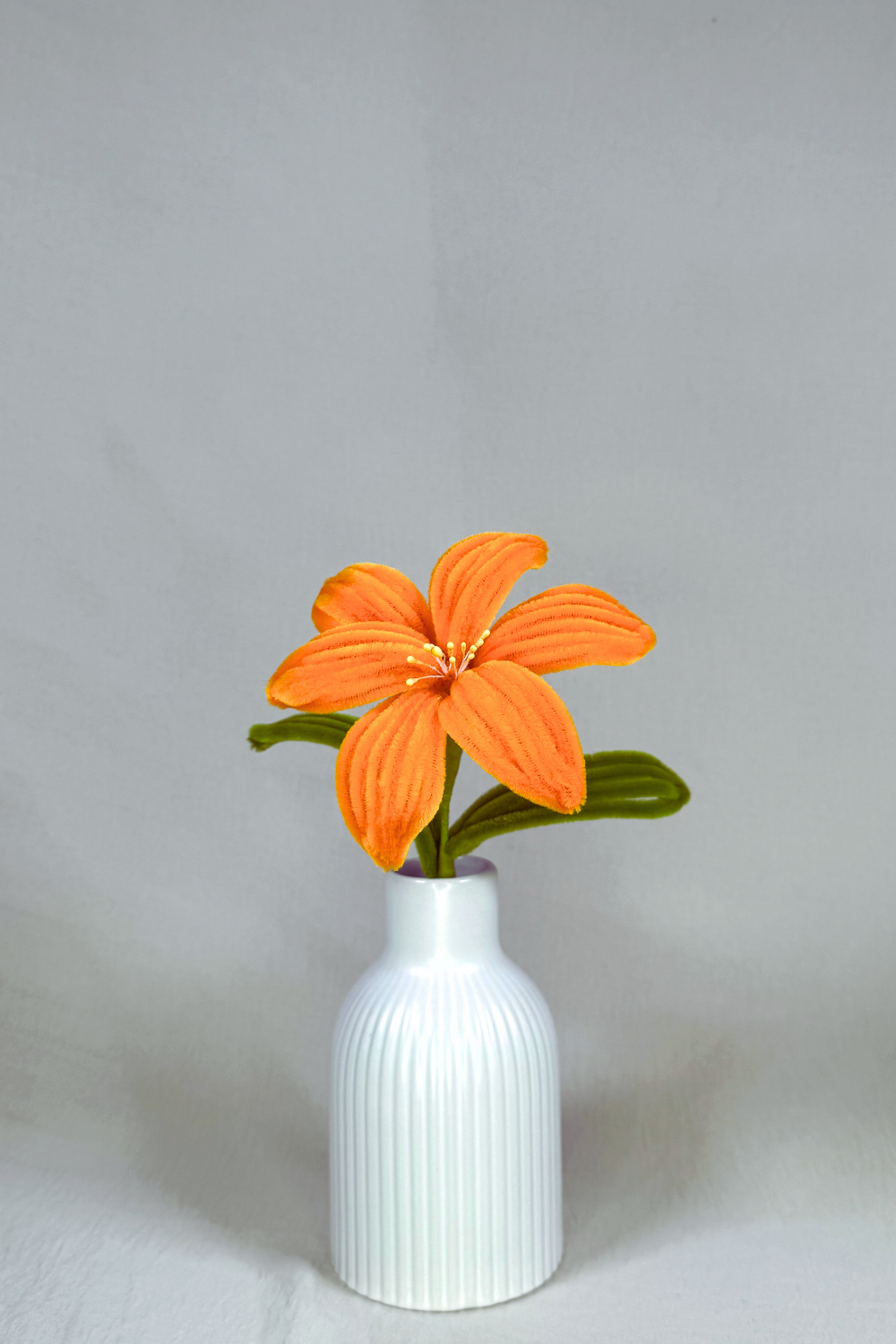Giglio arancione in scovolini in un vaso bianco su sfondo neutro - il fiore è fatto a mano 34 cm – fiore artigianale decorativo realizzato in Italia da Made By Hand.