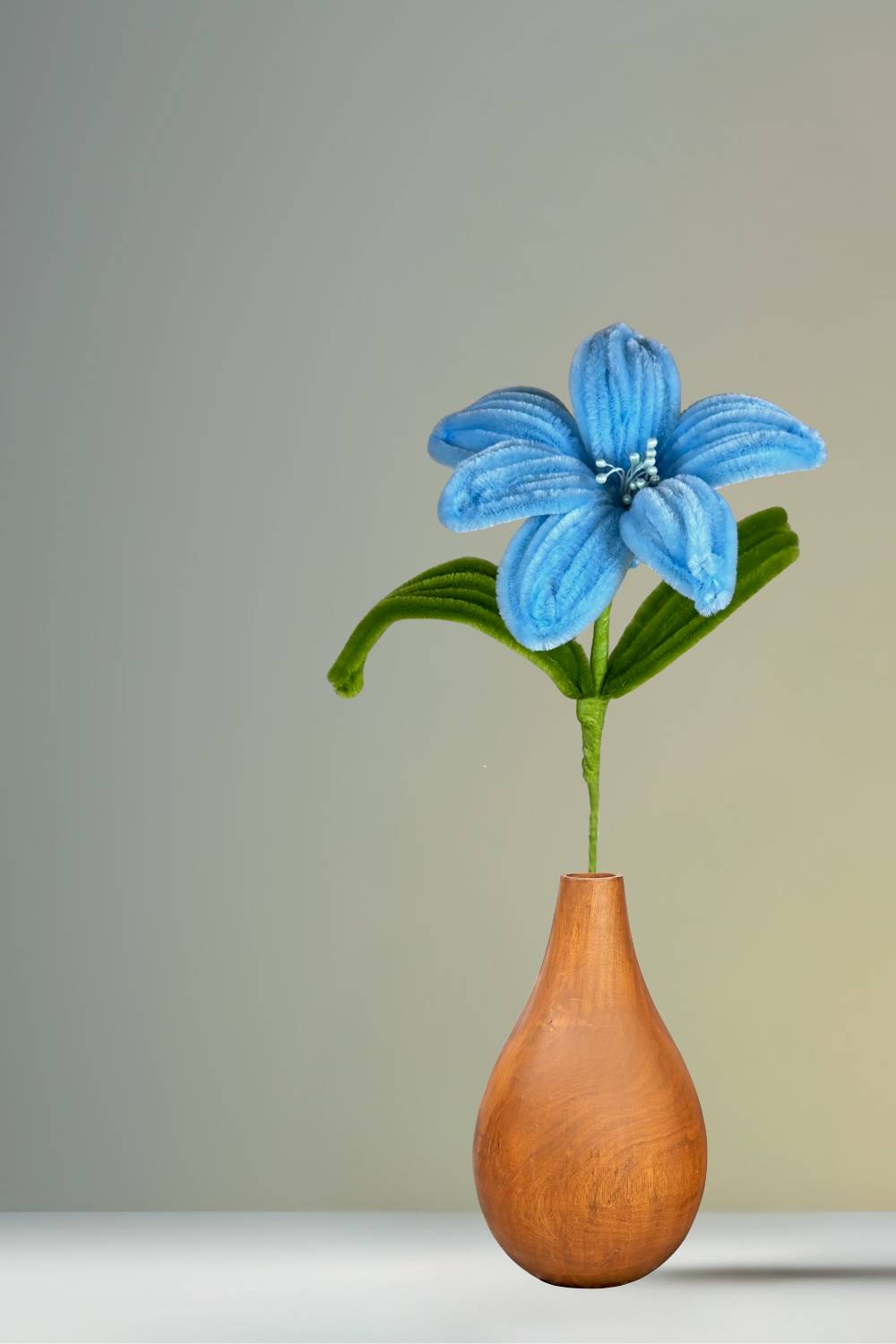 Giglio azzurro in scovolini in un vaso di legno su sfondo neutro - il fiore è fatto a mano 34 cm – fiore artigianale decorativo realizzato in Italia da Made By Hand.