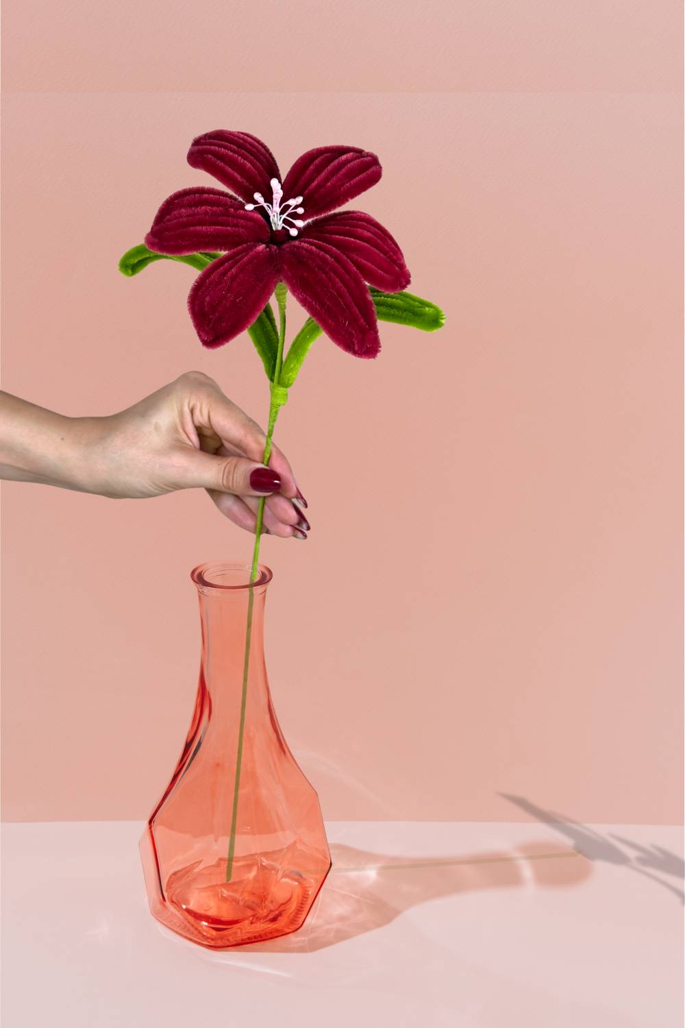 Giglio bordeaux in scovolini in un vaso di di vetro arancione su sfondo pesca - il fiore è fatto a mano 34 cm – fiore artigianale decorativo realizzato in Italia da Made By Hand.