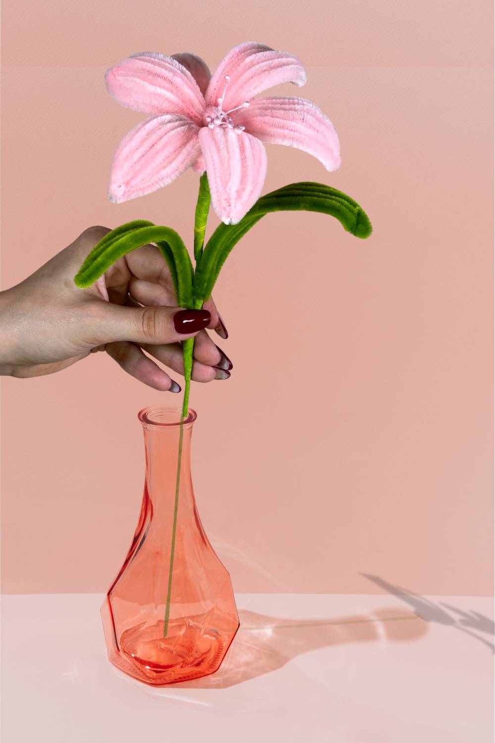 Giglio rosa in scovolini in un vaso di vetro arancione su sfondo pesca - il fiore è fatto a mano 34 cm – fiore artigianale decorativo realizzato in Italia da Made By Hand.