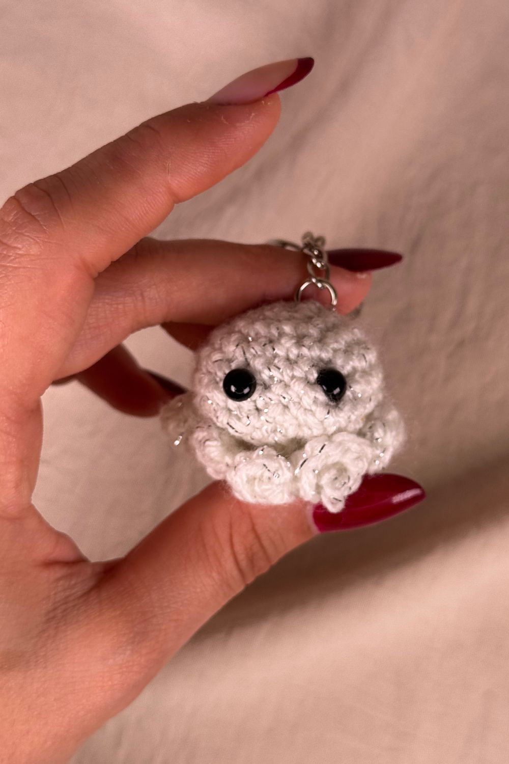 Portachiavi Polpetto bianco all’uncinetto artigianale Made By Hand tenuto in mano per mostrare le dimensioni reali, realizzato a mano con filato di qualità Made in Italy.