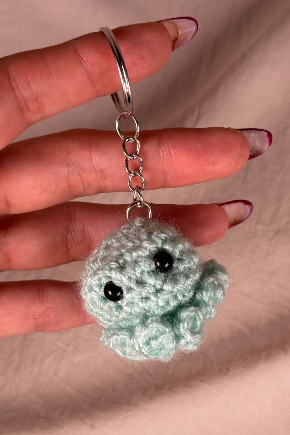 Portachiavi Polpetto tiffany all’uncinetto artigianale Made By Hand tenuto in mano per mostrare le dimensioni reali, realizzato a mano con filato di qualità Made in Italy.