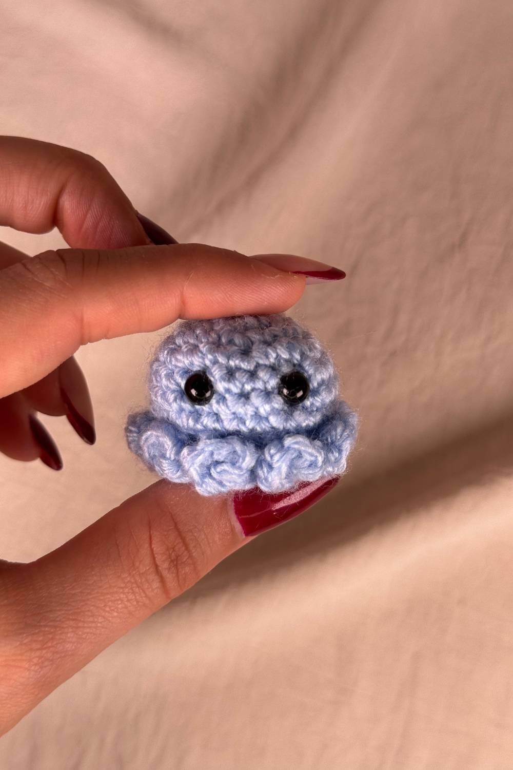 Portachiavi Polpetto azzurro all’uncinetto artigianale Made By Hand tenuto in mano per mostrare le dimensioni reali, realizzato a mano con filato di qualità Made in Italy.