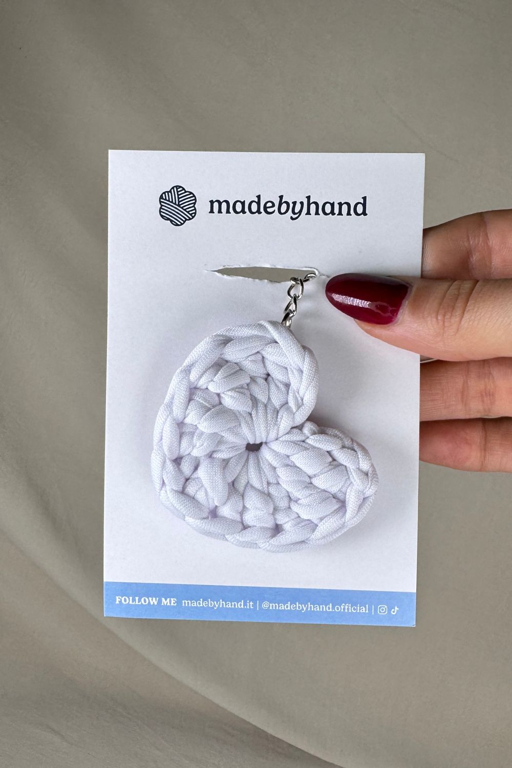 Portachiavi cuore bianco all’uncinetto Made By Hand, su cartoncino bianco con logo, perfetto come bomboniera o pensiero artigianale