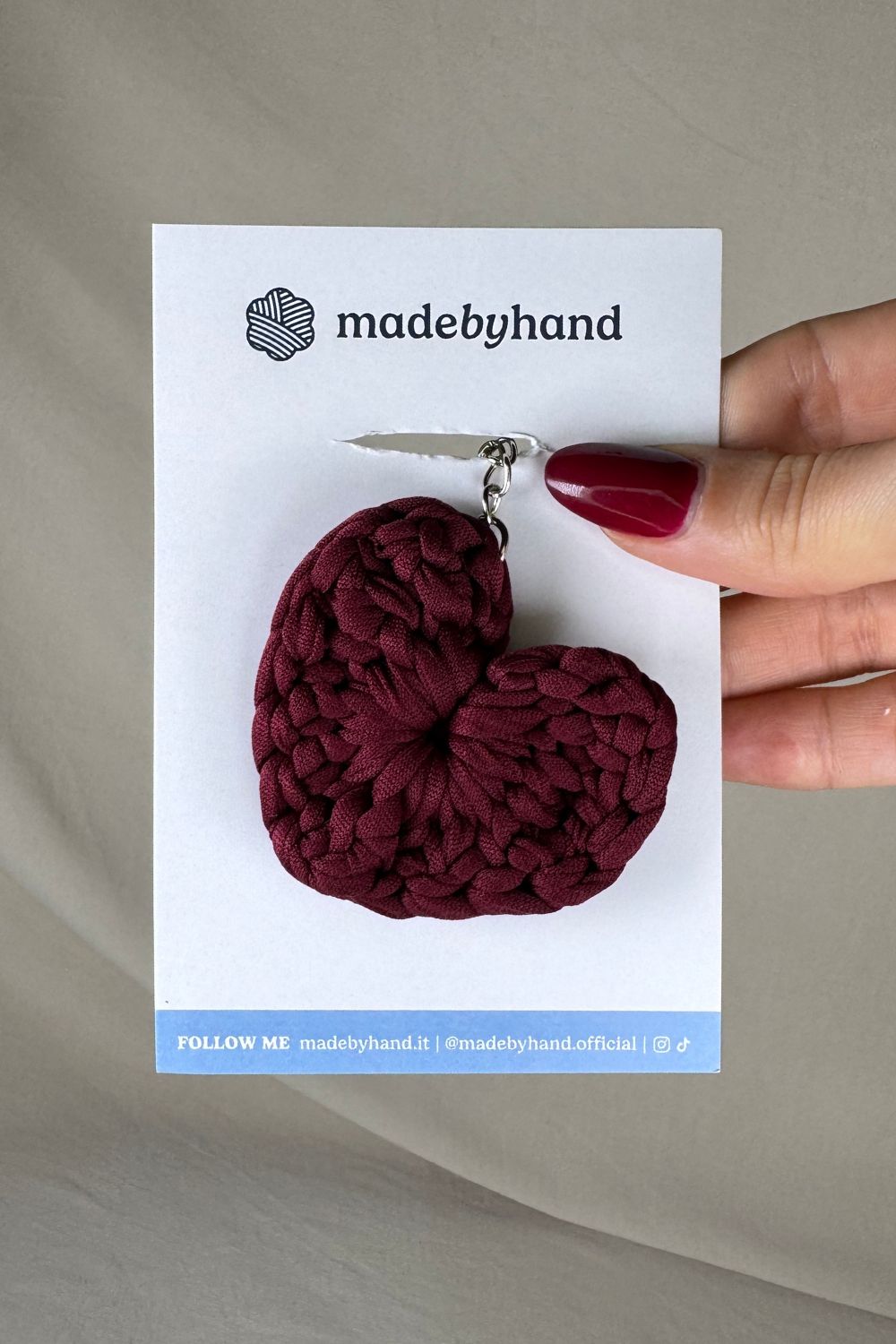 Portachiavi cuore bordeaux all’uncinetto Made By Hand, su cartoncino bianco con logo, ideale come bomboniera o accessorio artigianale