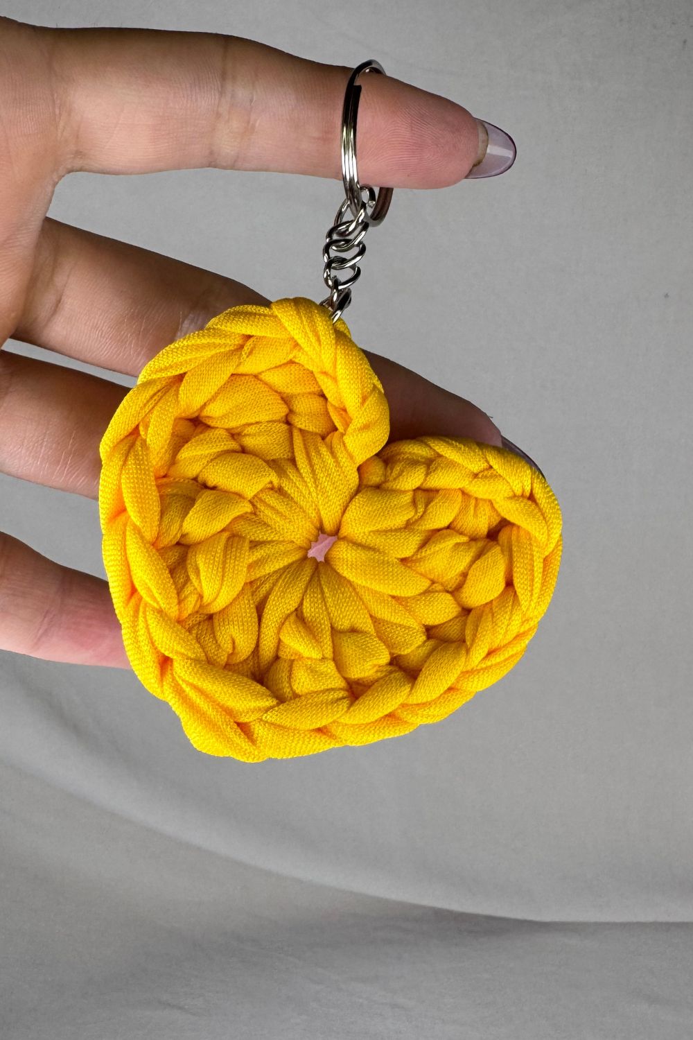 Portachiavi cuore giallo in fettuccia lavorato all’uncinetto, realizzato a mano in Italia da Made By Hand, mostrato in mano per evidenziare dimensioni e texture