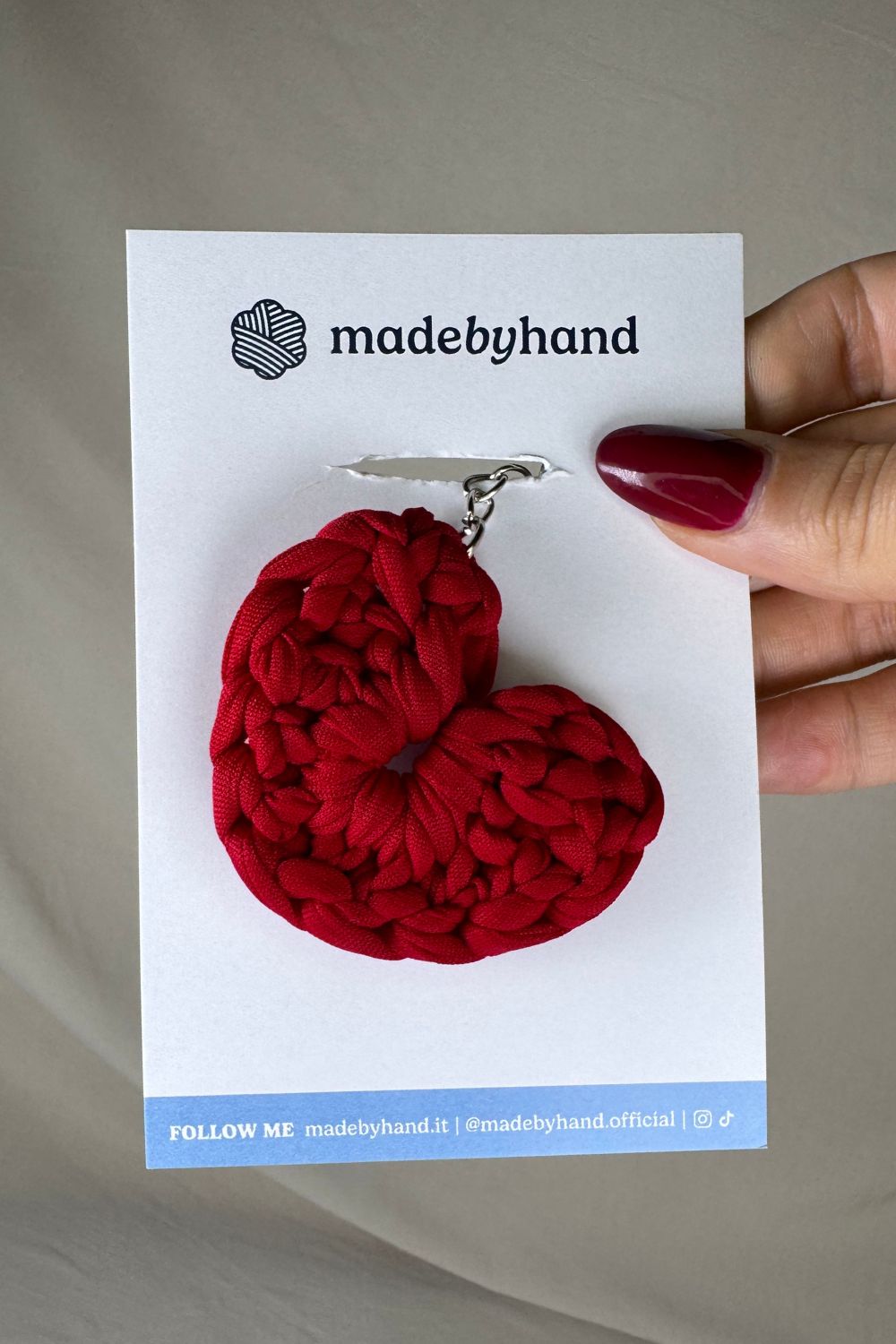Portachiavi cuore rosso Made By Hand, in fettuccia all’uncinetto, confezionato su cartoncino bianco con logo, perfetto come bomboniera o dono romantico