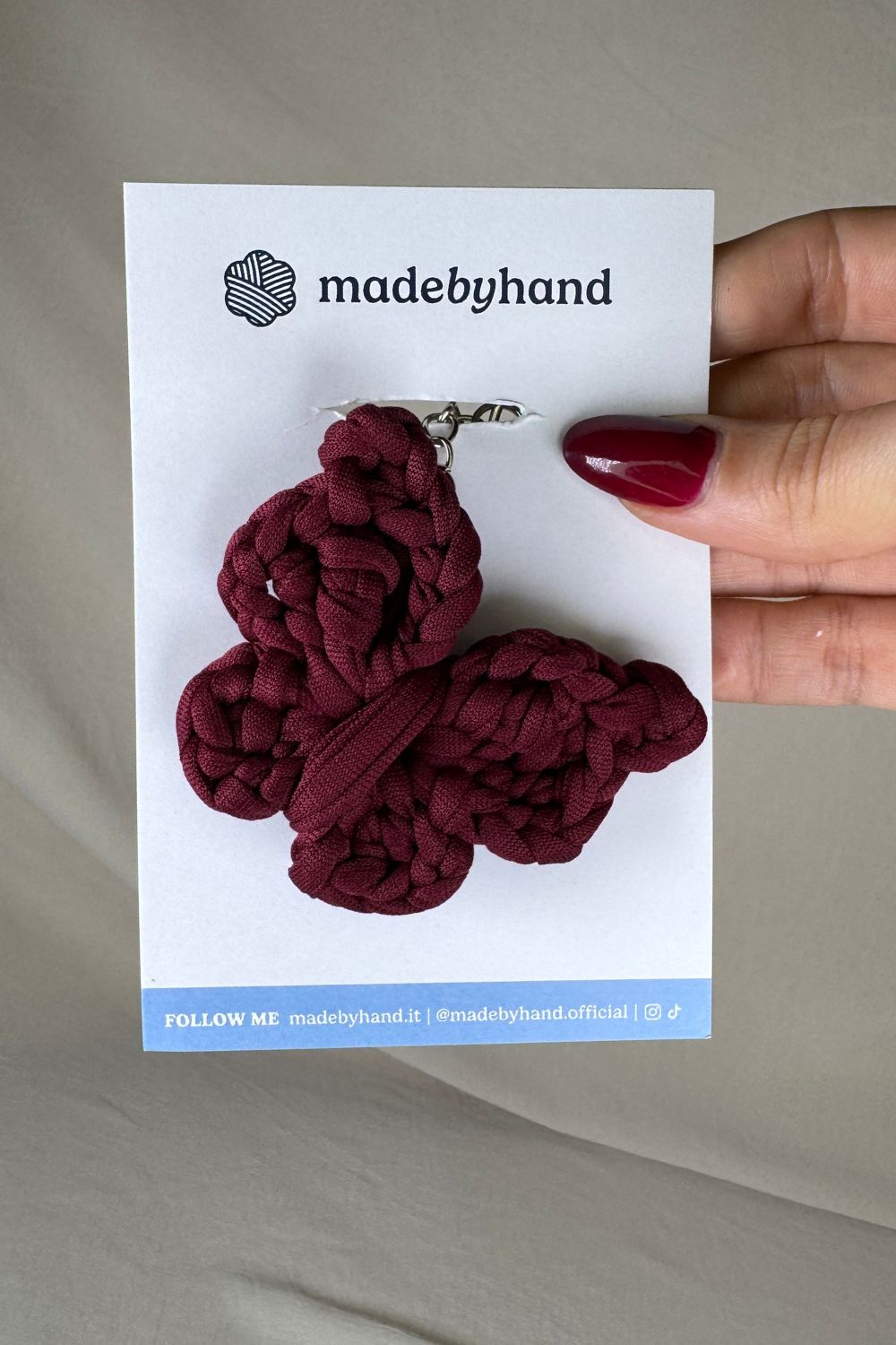 Portachiavi farfalla bordeaux all’uncinetto Made By Hand, su cartoncino bianco con logo, ideale come bomboniera o accessorio artigianale