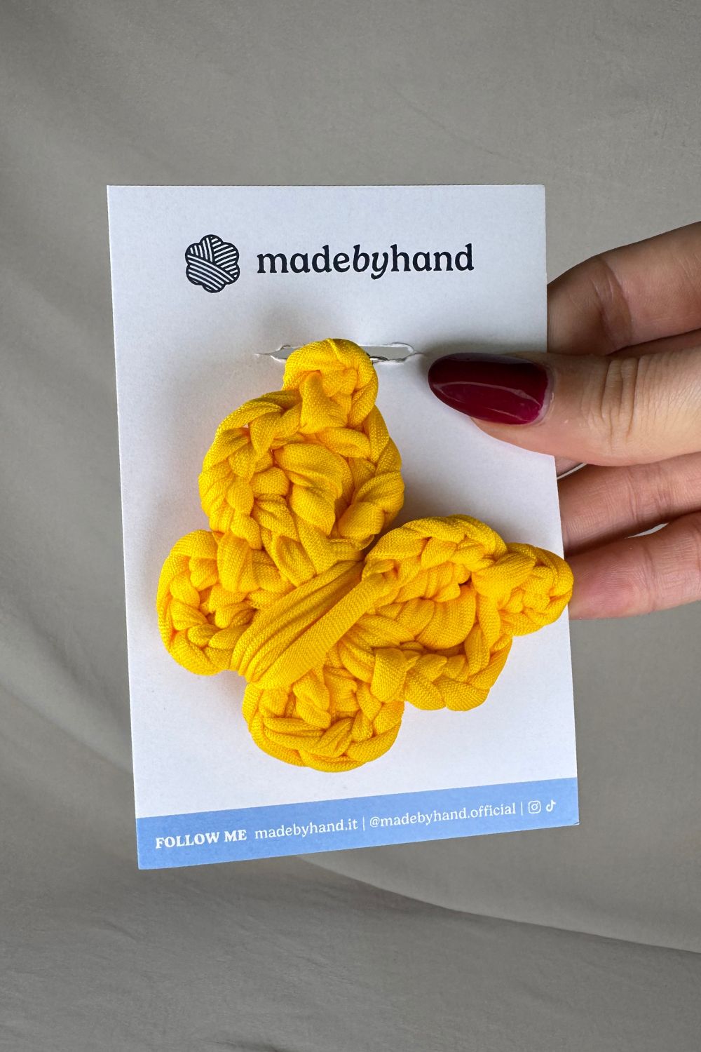 Portachiavi farfalla gialla all’uncinetto Made By Hand, su cartoncino bianco con logo, allegro e luminoso, perfetto come bomboniera o piccolo dono artigianale