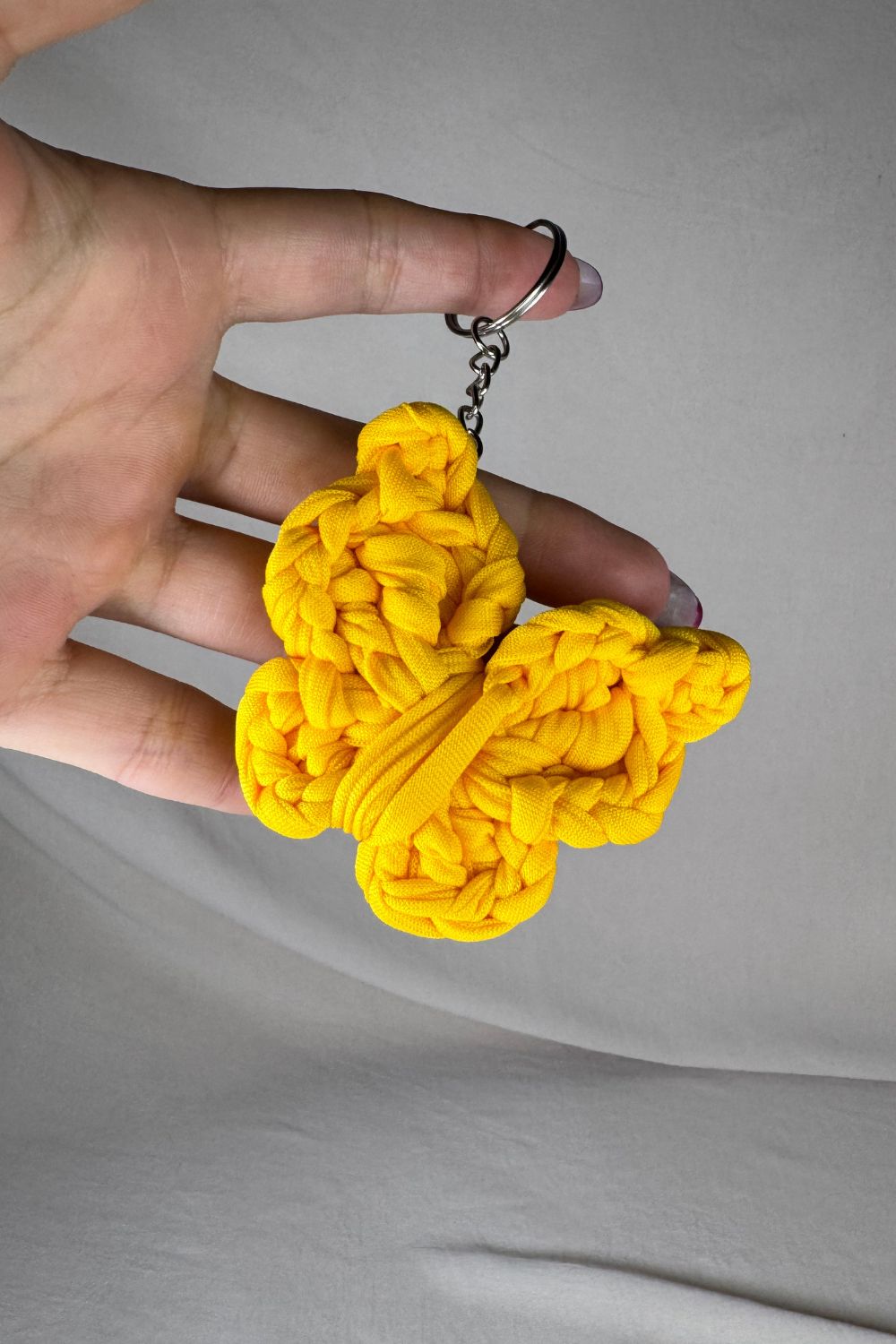 Portachiavi a farfalla gialla realizzato all’uncinetto, fatto a mano in Italia da Made By Hand, mostrato in mano per evidenziare le dimensioni e la texture