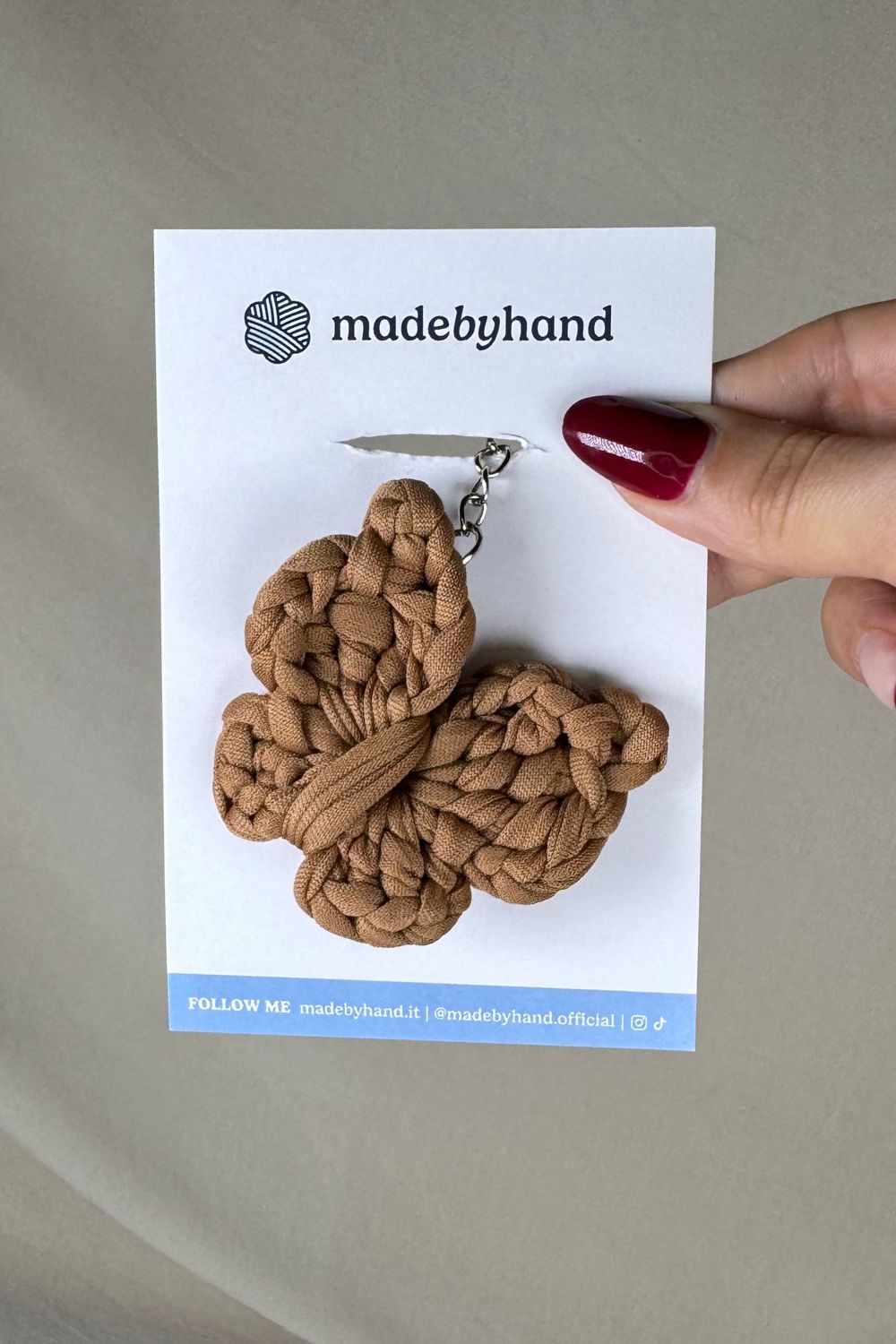 Portachiavi farfalla nocciola Made By Hand, su cartoncino bianco con logo, in stile naturale e minimal, perfetto come pensiero artigianale