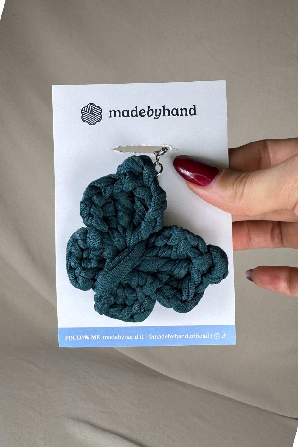 Portachiavi farfalla petrolio all’uncinetto Made By Hand, su cartoncino bianco con logo, ideale come bomboniera o piccolo dono fatto a mano