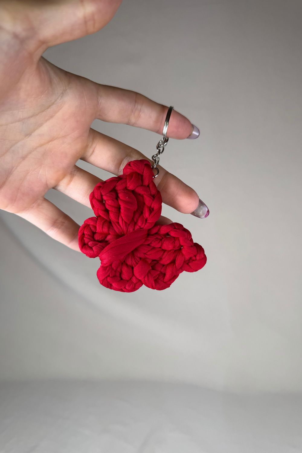 Portachiavi a farfalla rossa realizzato all’uncinetto, fatto a mano in Italia da Made By Hand, mostrato in mano come simbolo di passione e artigianalità