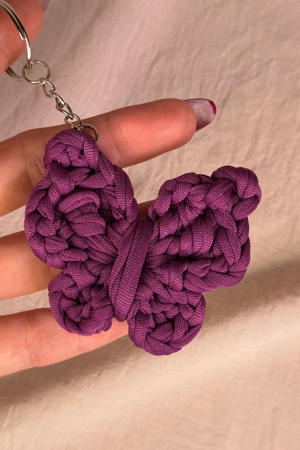 Portachiavi a farfalla viola realizzato all’uncinetto, fatto a mano in Italia da Made By Hand, mostrato in mano per evidenziare dimensioni e dettagli