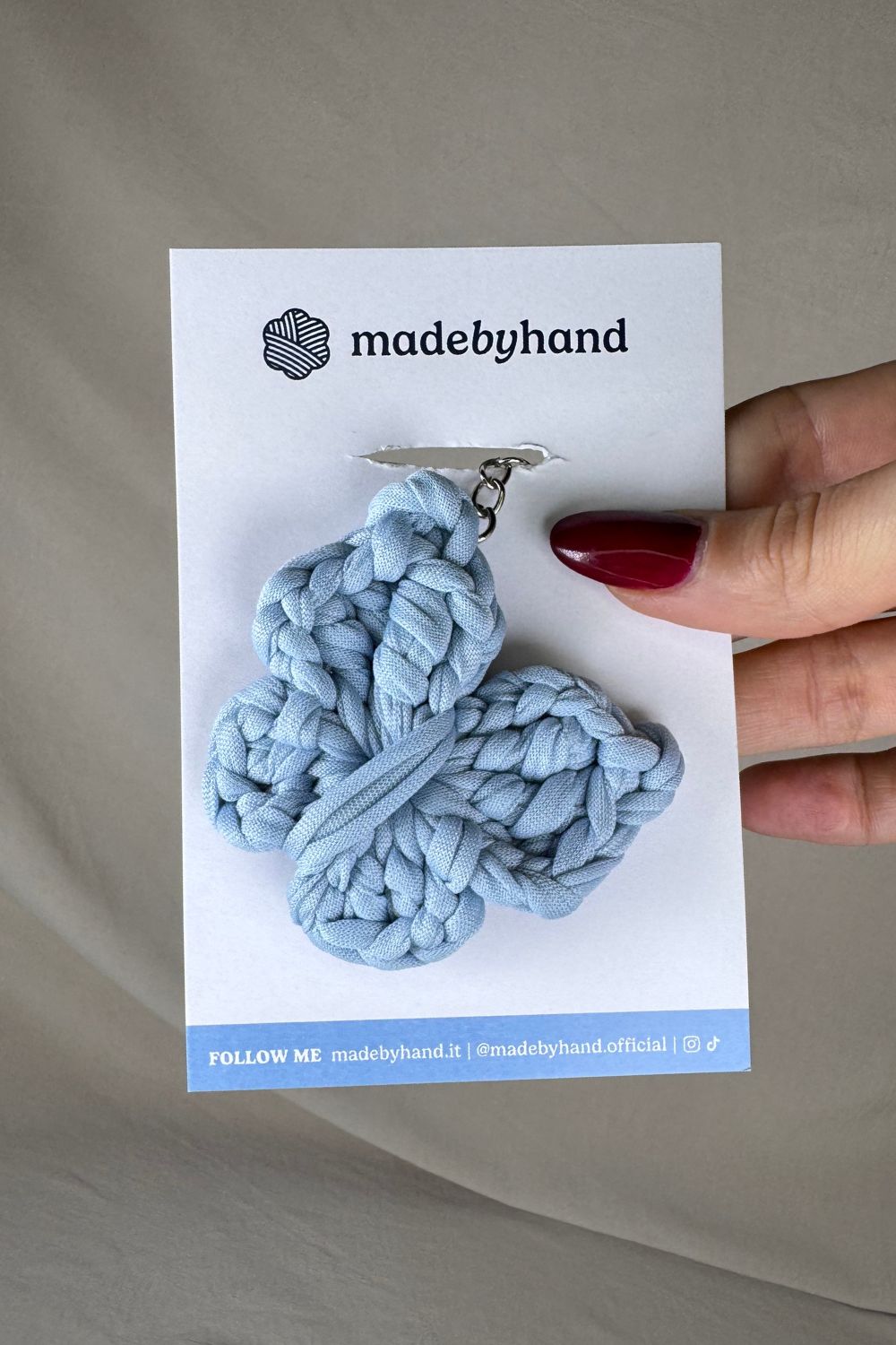 Portachiavi farfalla azzurra all’uncinetto Made By Hand, su cartoncino bianco con logo, ideale come bomboniera o piccolo regalo artigianale