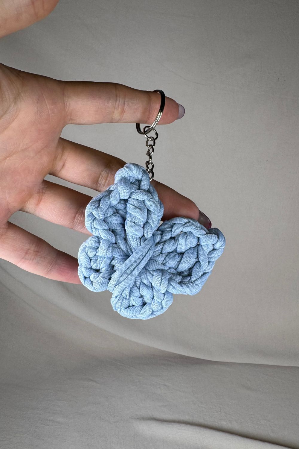 Portachiavi a forma di farfalla azzurra realizzato all’uncinetto, fatto a mano in Italia da Made By Hand, mostrato in mano per evidenziare dimensioni e dettagli artigianali