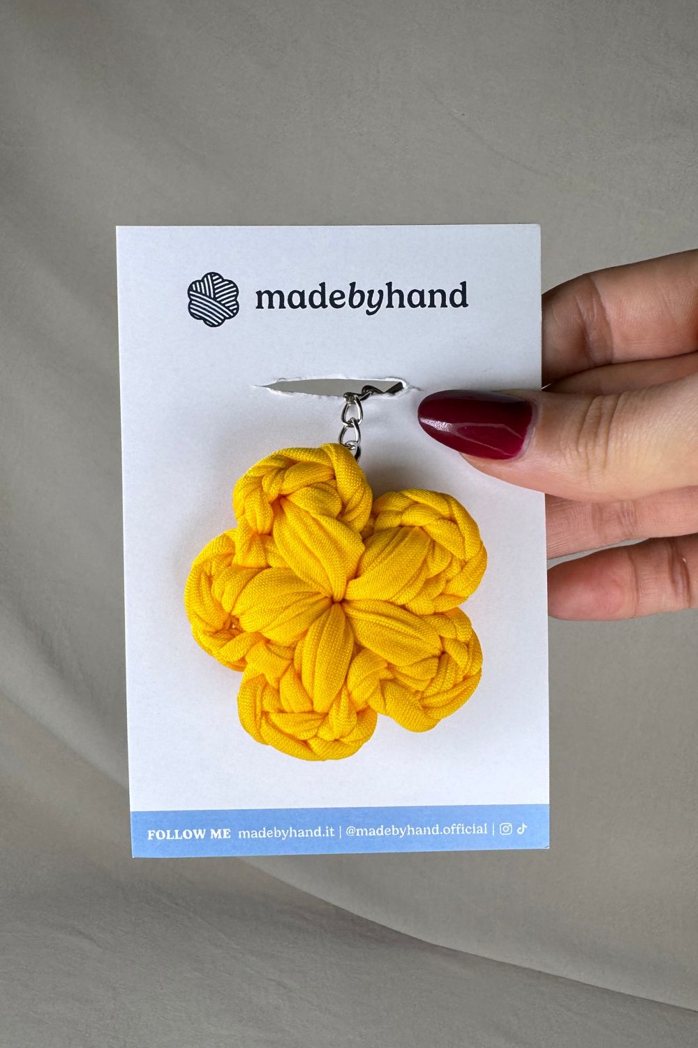 Portachiavi fiore giallo all’uncinetto Made By Hand, su cartoncino bianco con logo, allegro e solare, perfetto come bomboniera o piccolo dono artigianale