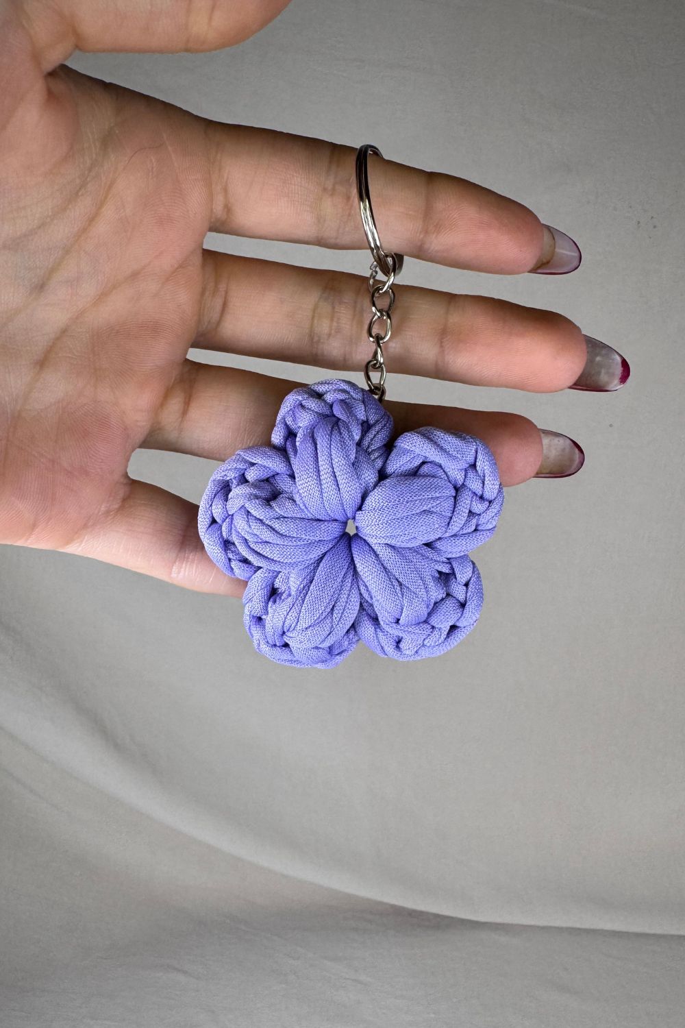 Dettaglio ravvicinato del portachiavi fiore lilla Made By Hand, che mette in luce la delicatezza e la lavorazione all’uncinetto artigianale
