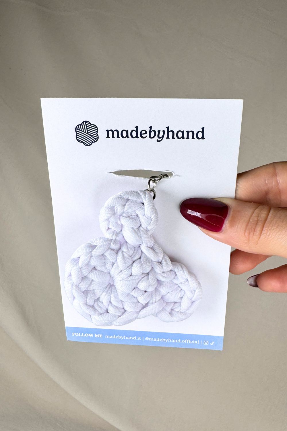 Portachiavi orsetto bianco all’uncinetto Made By Hand, su cartoncino bianco con logo, perfetto come bomboniera o piccolo regalo artigianale
