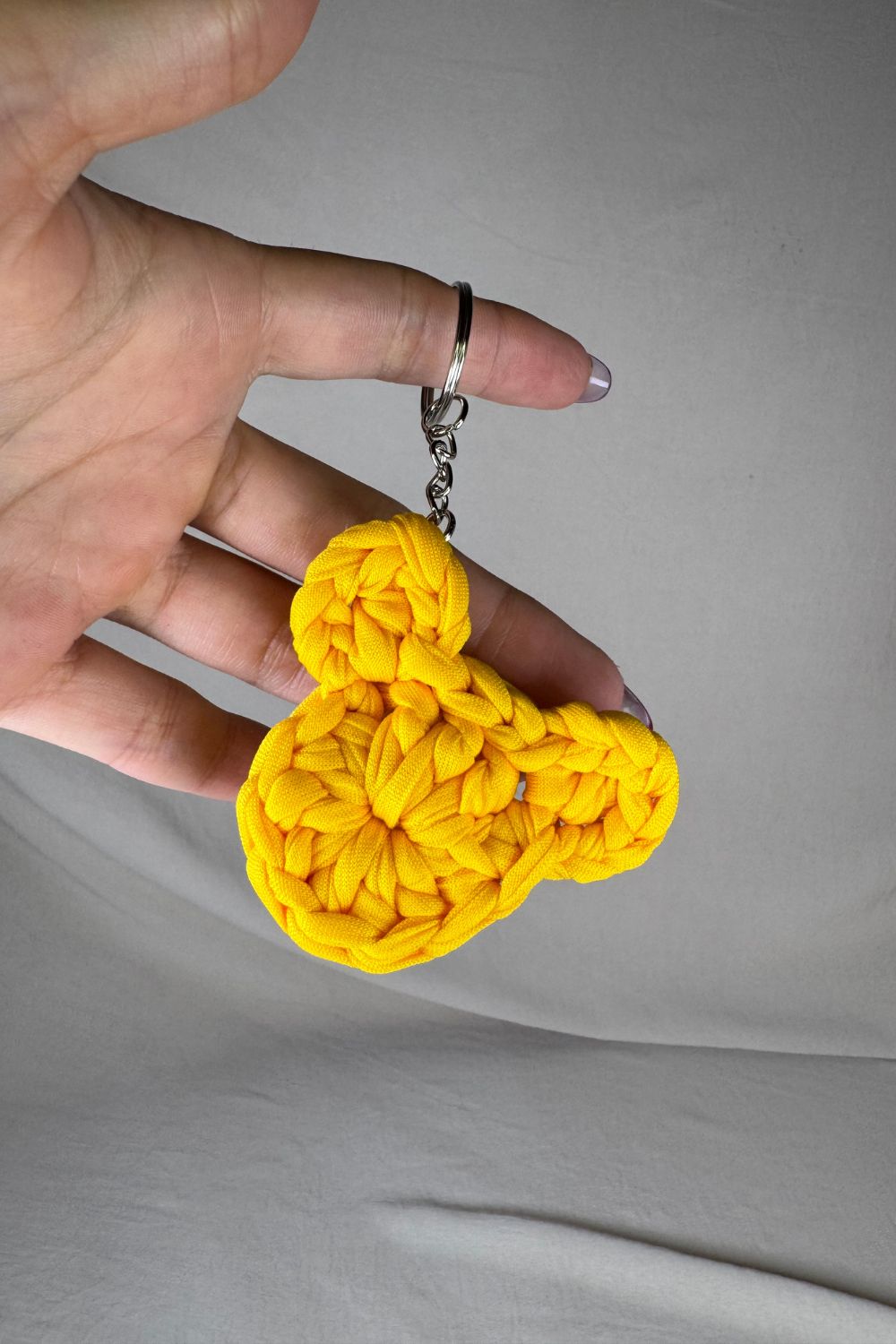 Portachiavi a forma di orsetto giallo realizzato all’uncinetto, fatto a mano in Italia da Made By Hand, mostrato in mano per evidenziare la grandezza