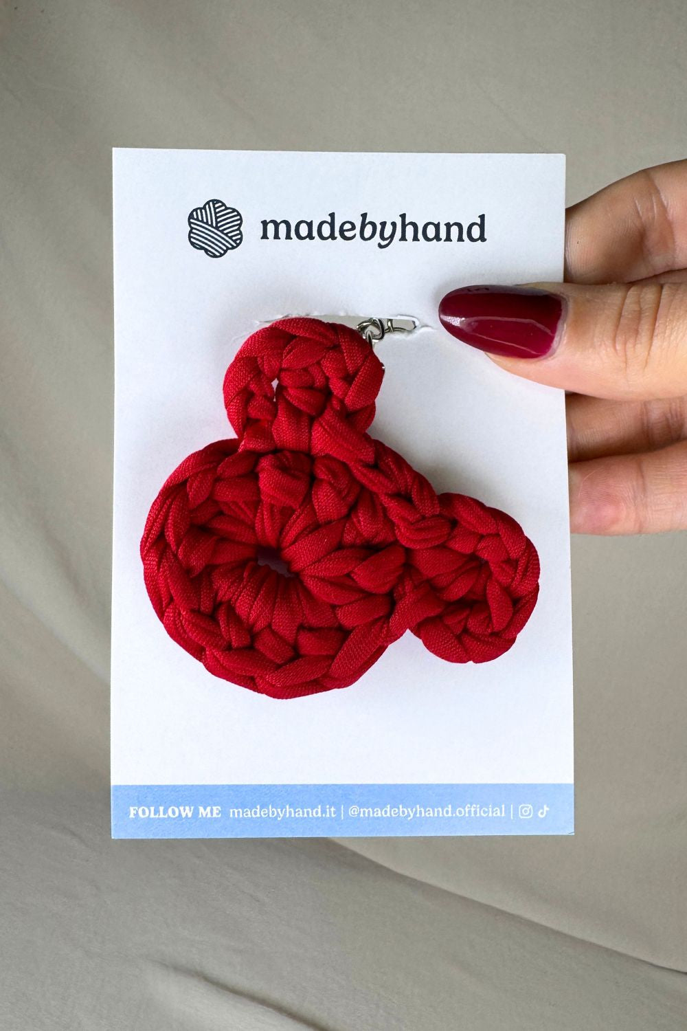 Portachiavi orsetto rosso all’uncinetto Made By Hand, su cartoncino bianco con logo, perfetto come bomboniera o regalo romantico