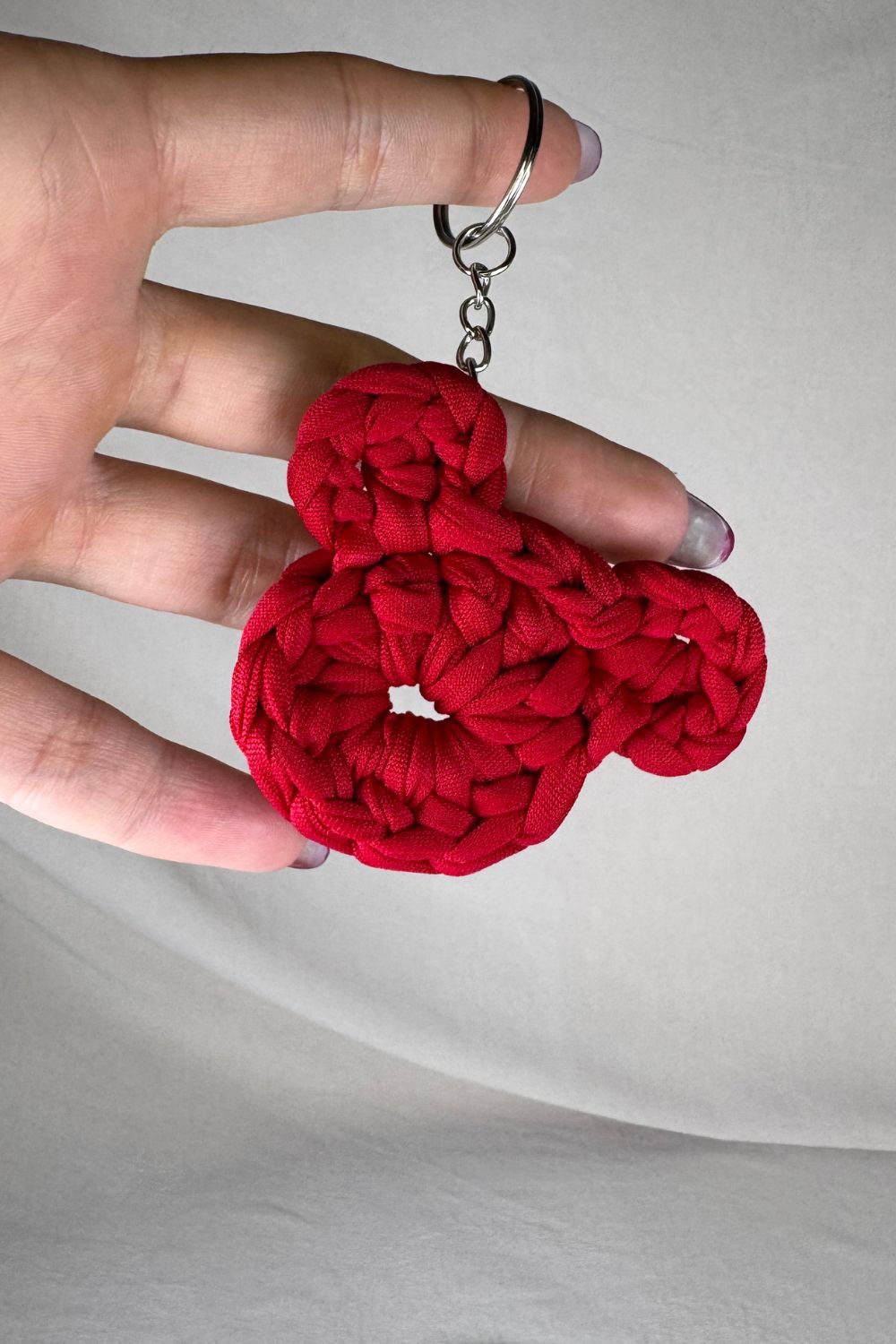 Portachiavi a forma di orsetto rosso lavorato all’uncinetto, fatto a mano in Italia da Made By Hand, mostrato in mano come simbolo d’amore e artigianalità