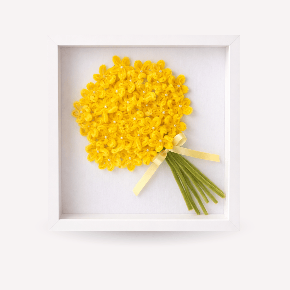 Quadro ricordo artigianale con cornice bianca, bouquet di fiori gialli fatti a mano con piccoli dettagli luminosi, fiocco giallino e steli verdi. Decorazione elegante e personalizzabile, adatta come idea regalo per la festa della mamma o complemento d’arredo