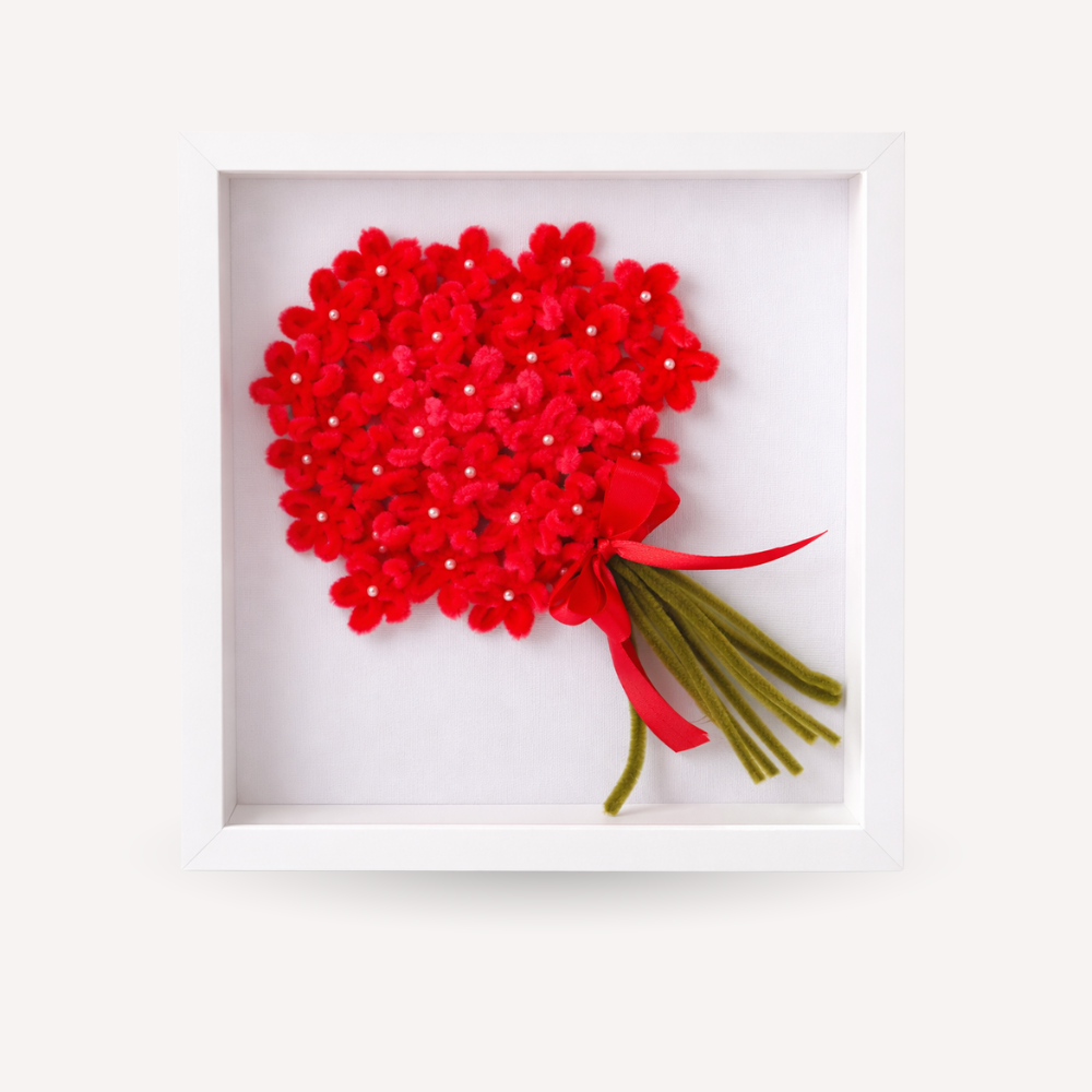 Quadro ricordo artigianale con cornice bianca, bouquet di fiori rissi fatti a mano con piccoli dettagli luminosi, fiocco rosso e steli verdi. Decorazione elegante e personalizzabile, adatta come idea regalo o complemento d’arredo