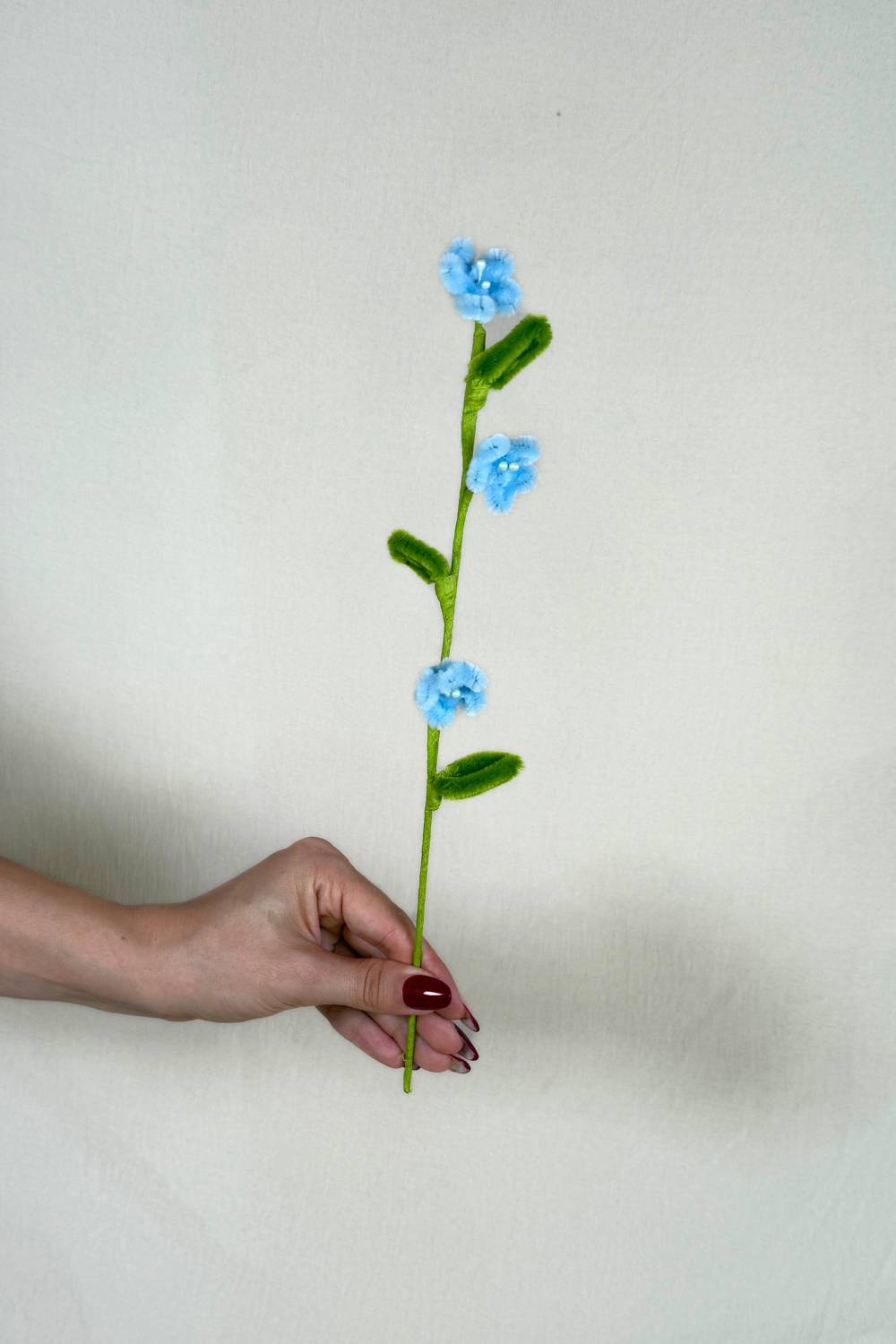 Rametto con 3 mini margherite azzurre in scovolini, fatto a mano da Made By Hand in Italia, fiore artigianale decorativo 34 cm ideale per mazzi o regali floreali sostenibili. Made by hand crea fiori con scovolini colorati fatti a mano in italia.