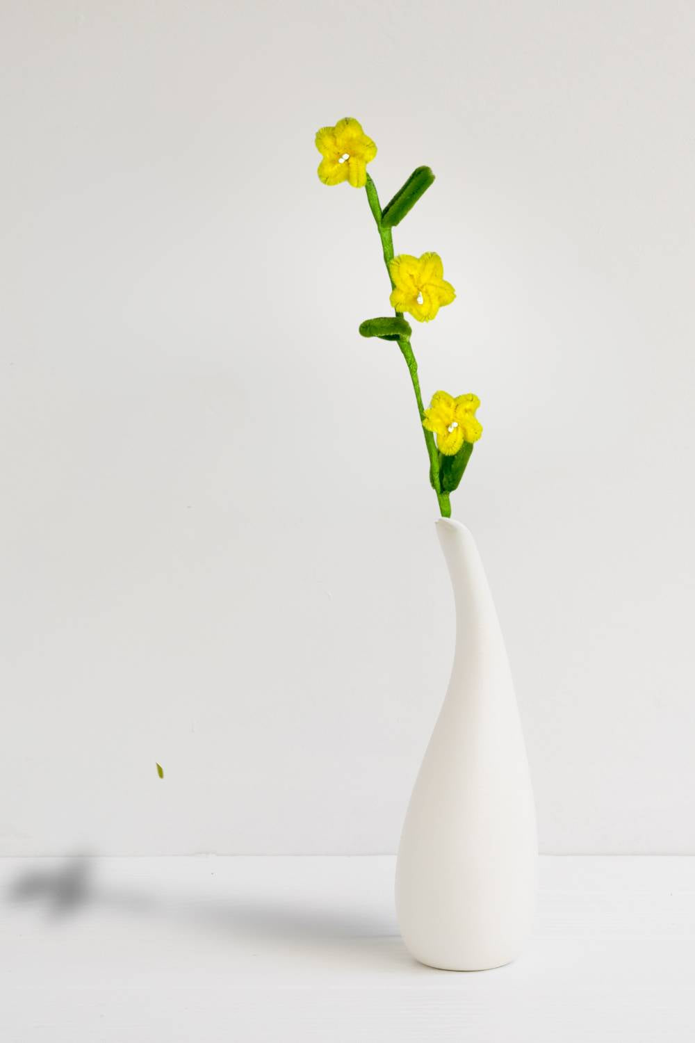 In un vaso, un rametto con 3 mini margherite gialle in scovolini, fatto a mano da Made By Hand in Italia, fiore artigianale decorativo 34 cm ideale per mazzi o regali floreali sostenibili. Made by hand crea fiori con scovolini colorati fatti a mano in italia.