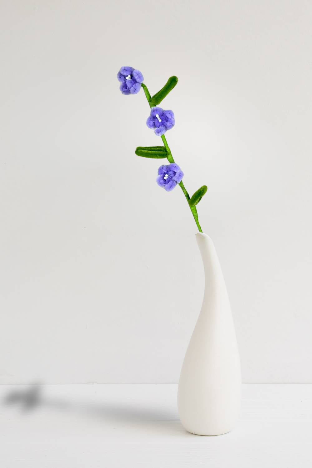 In un vaso, un rametto con 3 mini margherite lilla in scovolini, fatto a mano da Made By Hand in Italia, fiore artigianale decorativo 34 cm ideale per mazzi o regali floreali sostenibili. Made by hand crea fiori con scovolini colorati fatti a mano in italia.
