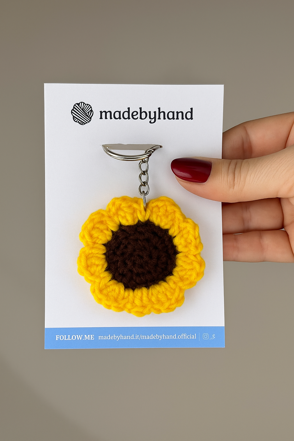 Portachiavi a girasole all’uncinetto Made By Hand confezionato a mano in Italia, idea regalo artigianale romantica e sostenibile, perfetta per ogni occasione specialePortachiavi a fiocco viola realizzato all’uncinetto, fatto a mano in Italia da Made By Hand, presentato su cartoncino bianco con logo, ideale come bomboniera o regalo artigianale sostenibile