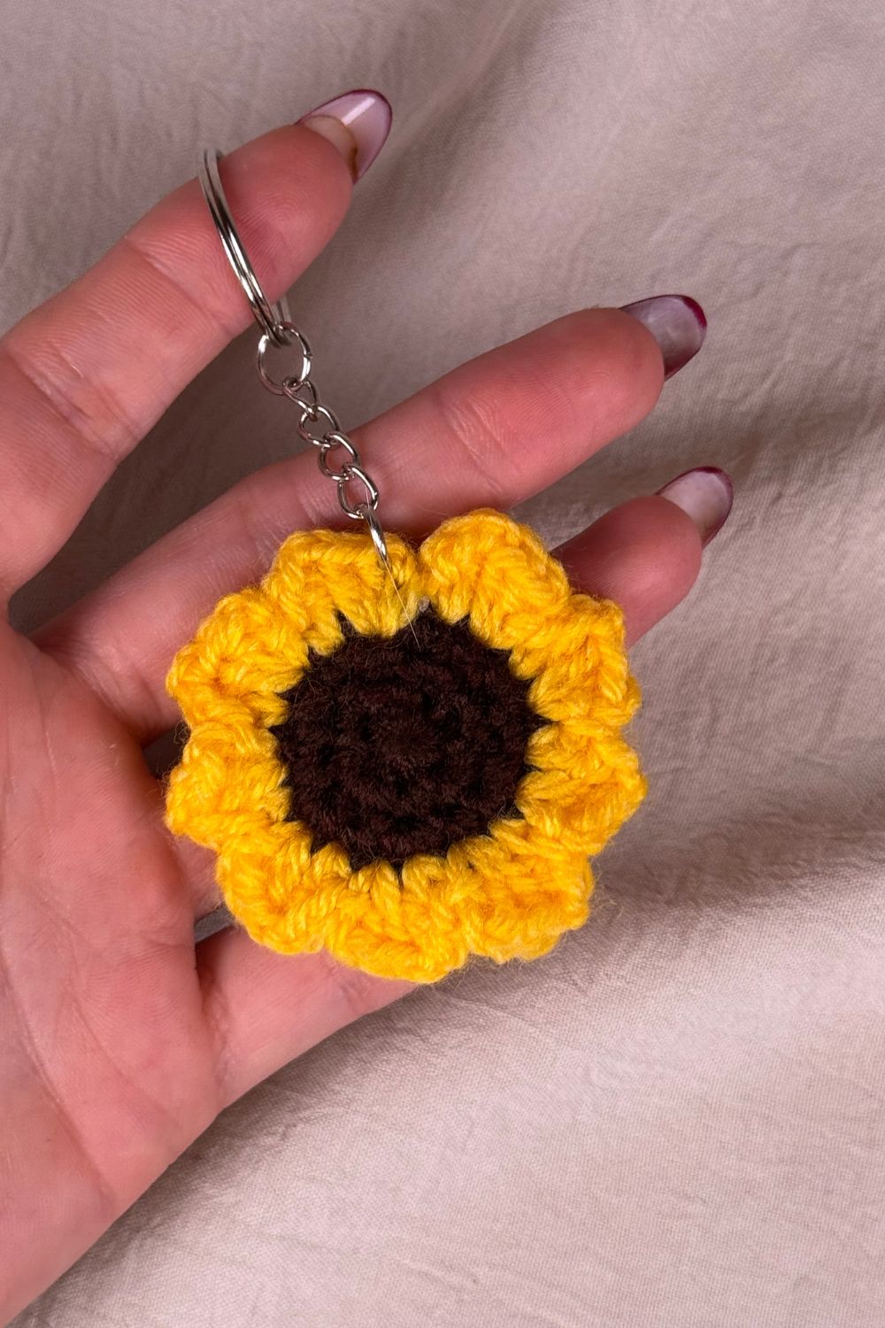 Portachiavi con girasole fatto a mano in Italia da Made By Hand, creazione artigianale in miniatura con fiore rosa all’uncinetto, mostrato in mano per evidenziare i dettagli e le dimensioni