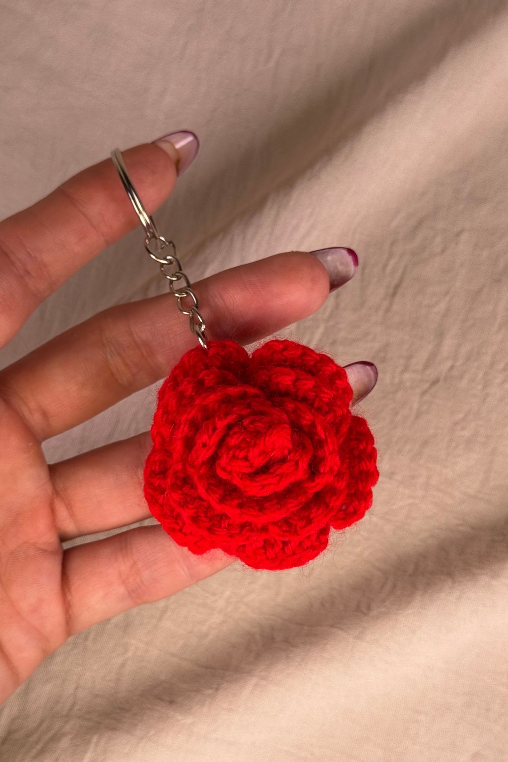 Portachiavi con rosa rossa fatto a mano in Italia da Made By Hand, creazione artigianale in miniatura con fiore rosa all’uncinetto, mostrato in mano per evidenziare i dettagli e le dimensioni