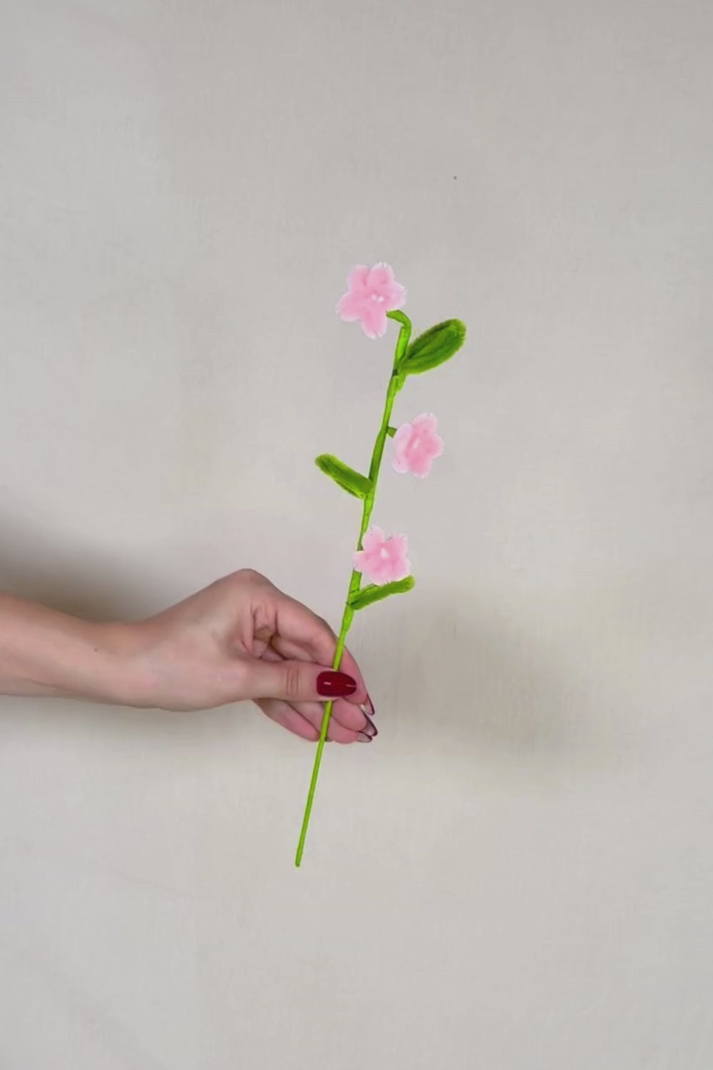 Video che fa vedere a 360 gradi un rametto con 3 mini margherite rosa chiaro in scovolini, fatto a mano da Made By Hand in Italia, fiore artigianale decorativo 34 cm ideale per mazzi o regali floreali sostenibili