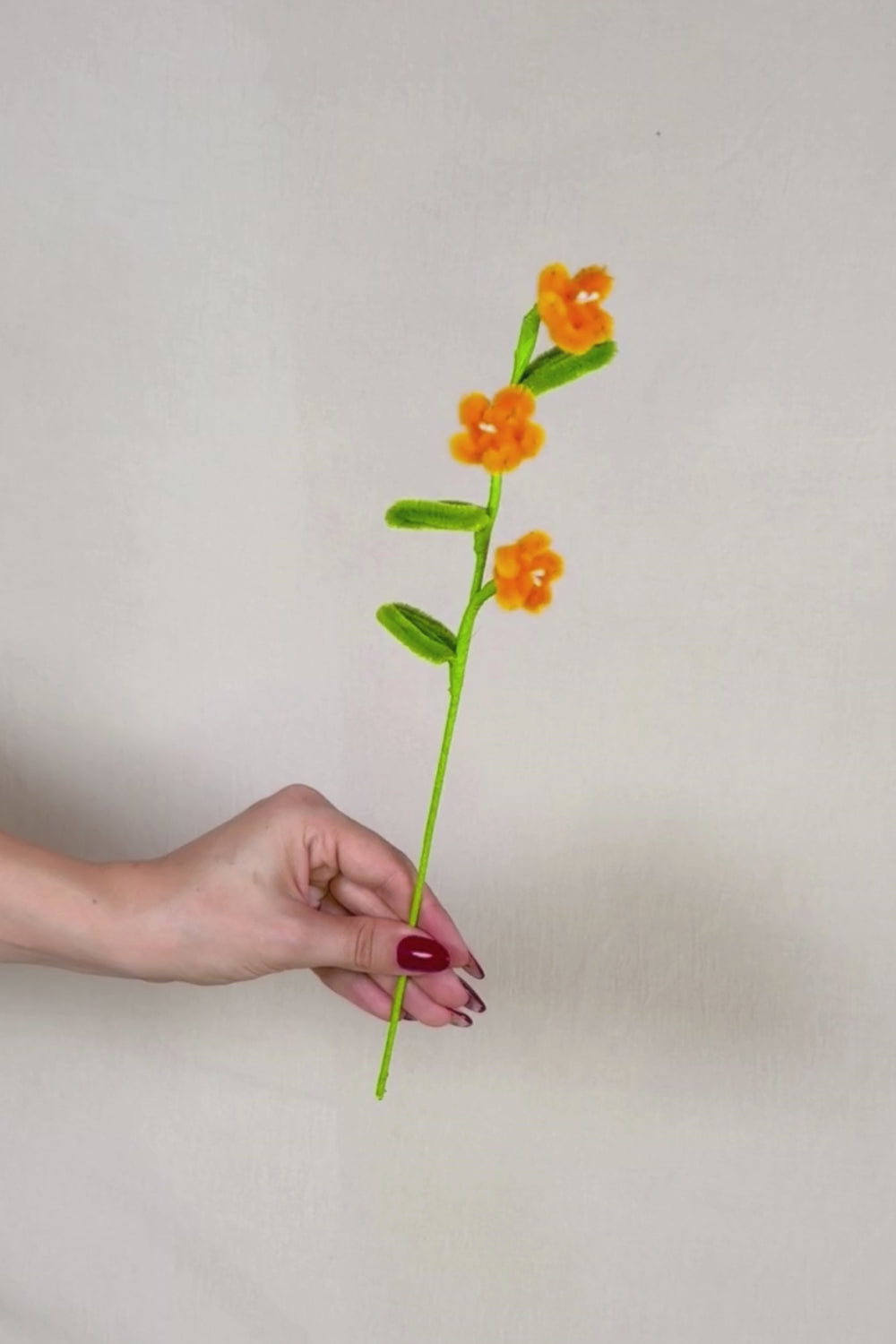 Video che fa vedere a 360 gradi un rametto con 3 mini margherite arancioni in scovolini, fatto a mano da Made By Hand in Italia, fiore artigianale decorativo 34 cm ideale per mazzi o regali floreali sostenibili