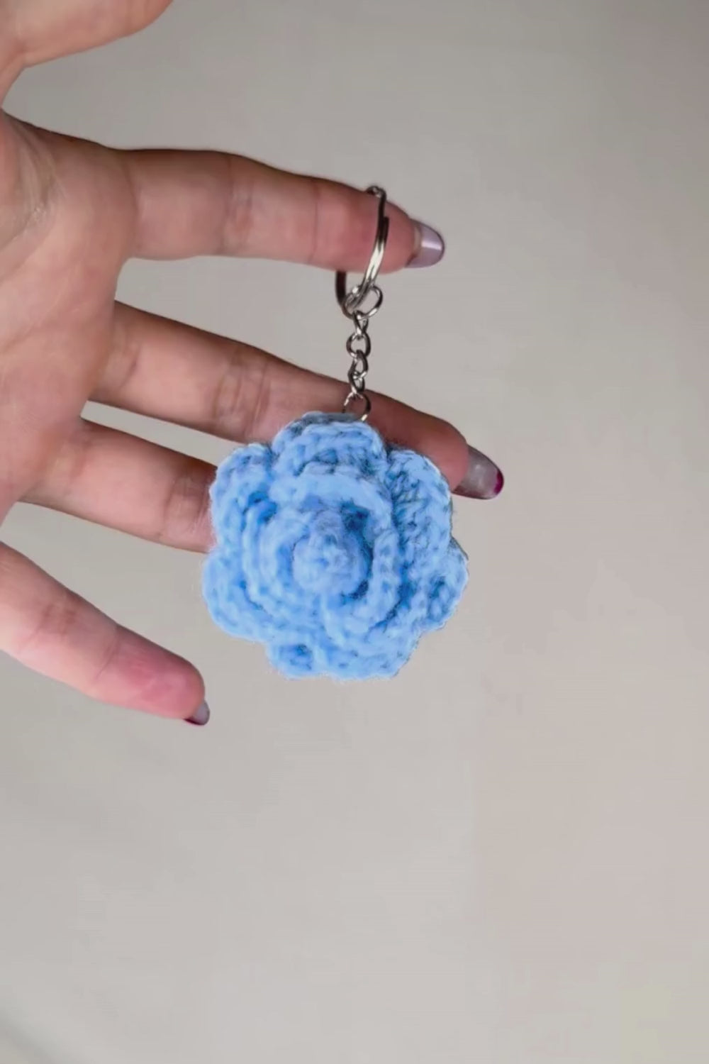 Video 360° del portachiavi con rosa azzurra fatto a mano in Italia da Made By Hand, creazione artigianale all’uncinetto mostrata in rotazione per evidenziare i dettagli del fiore