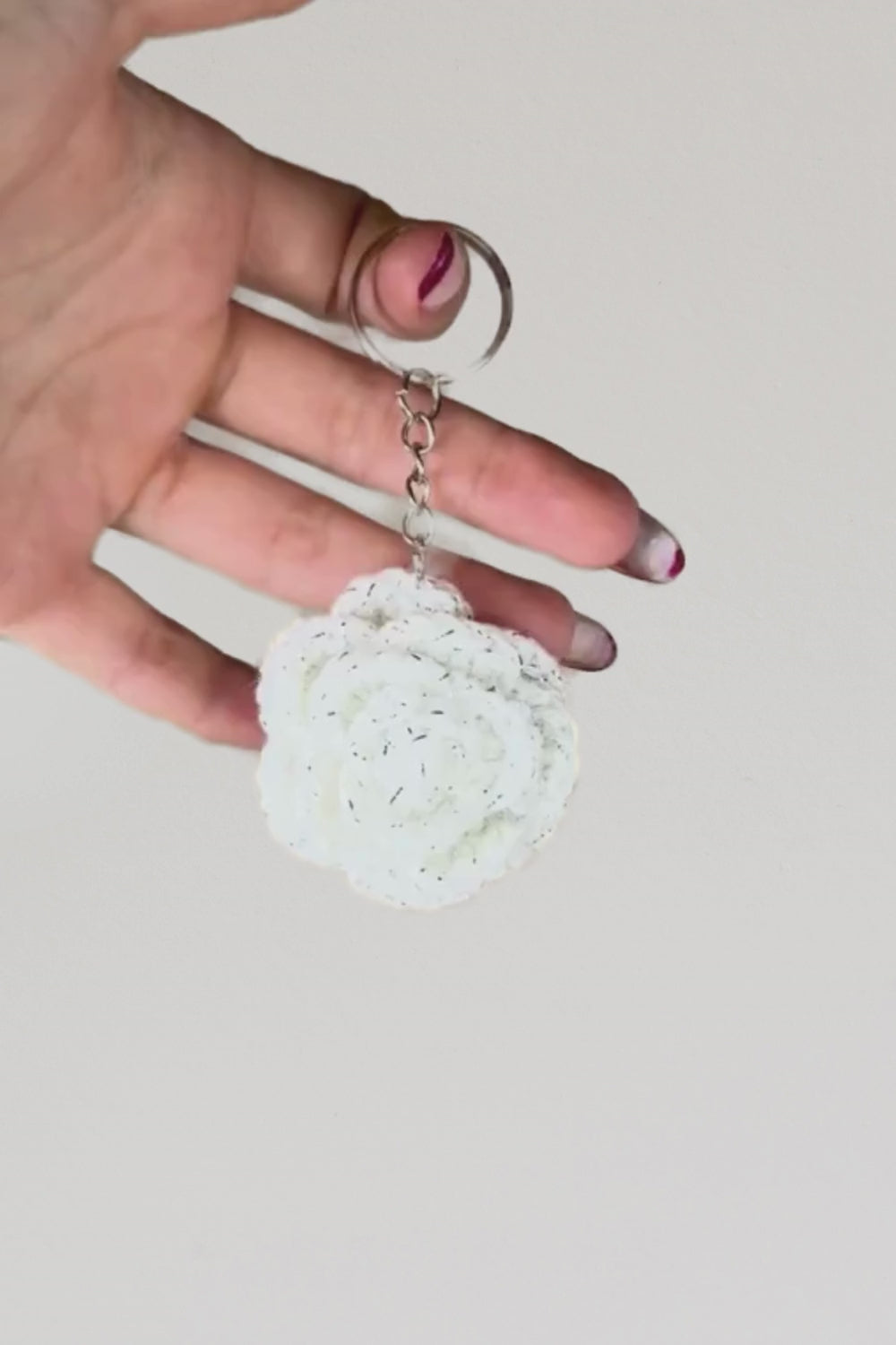 Video 360° del portachiavi con rosa bianca fatto a mano in Italia da Made By Hand, creazione artigianale all’uncinetto mostrata in rotazione per evidenziare i dettagli del fiore