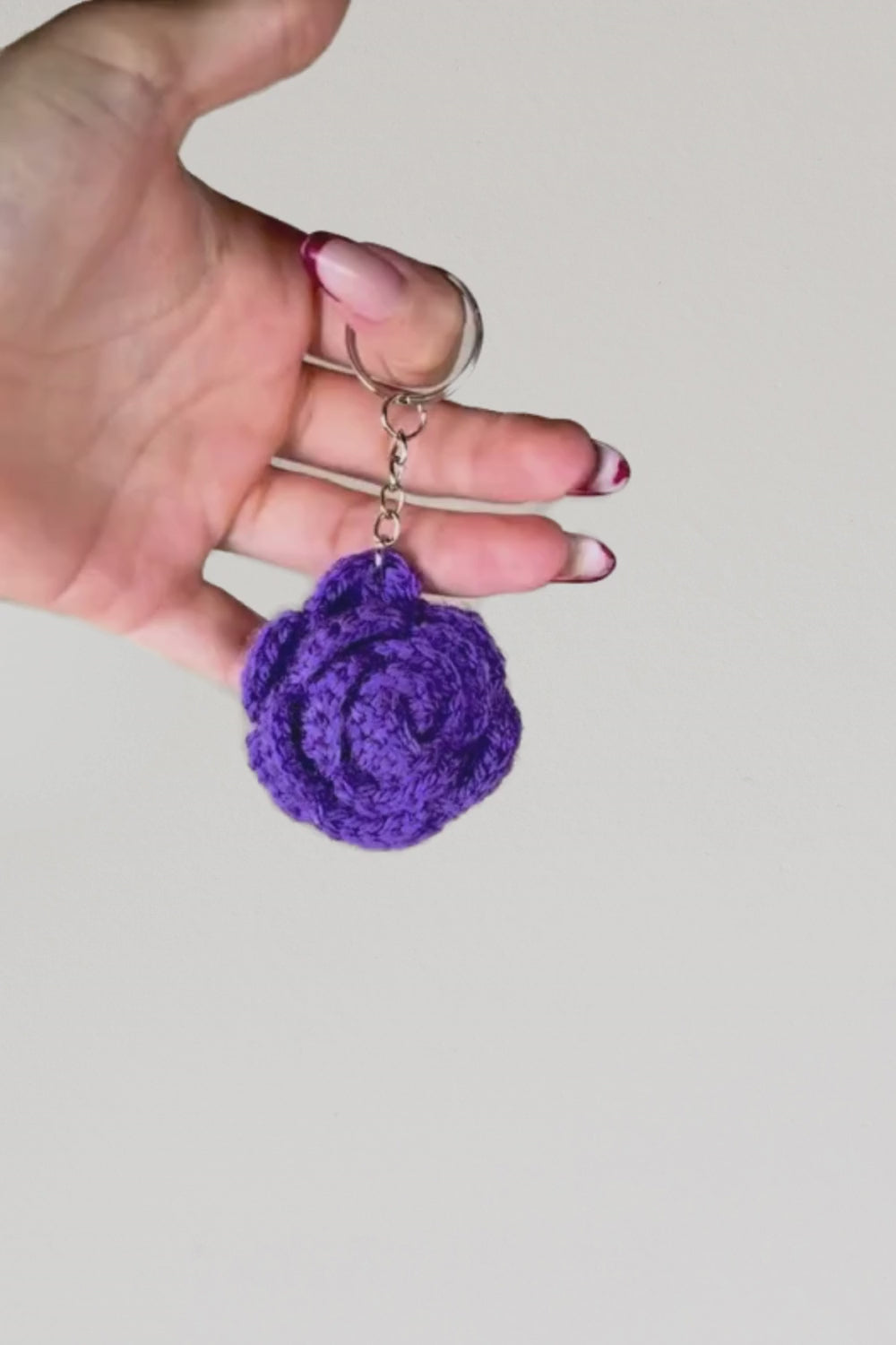 Video 360° del portachiavi con rosa viola fatto a mano in Italia da Made By Hand, creazione artigianale all’uncinetto mostrata in rotazione per evidenziare i dettagli del fiore