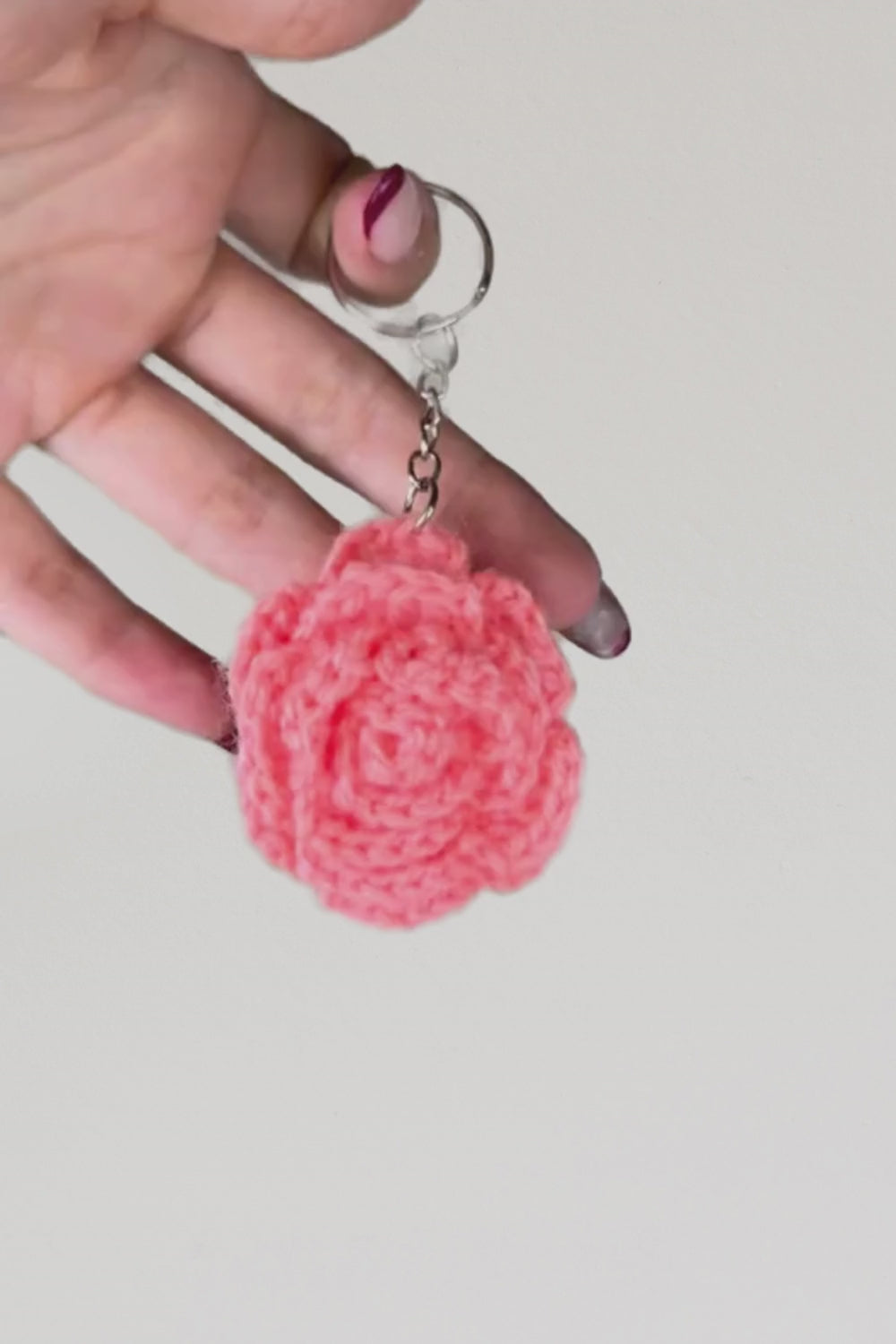 Video 360° del portachiavi con rosa rosa-salmone fatto a mano in Italia da Made By Hand, creazione artigianale all’uncinetto mostrata in rotazione per evidenziare i dettagli del fiore