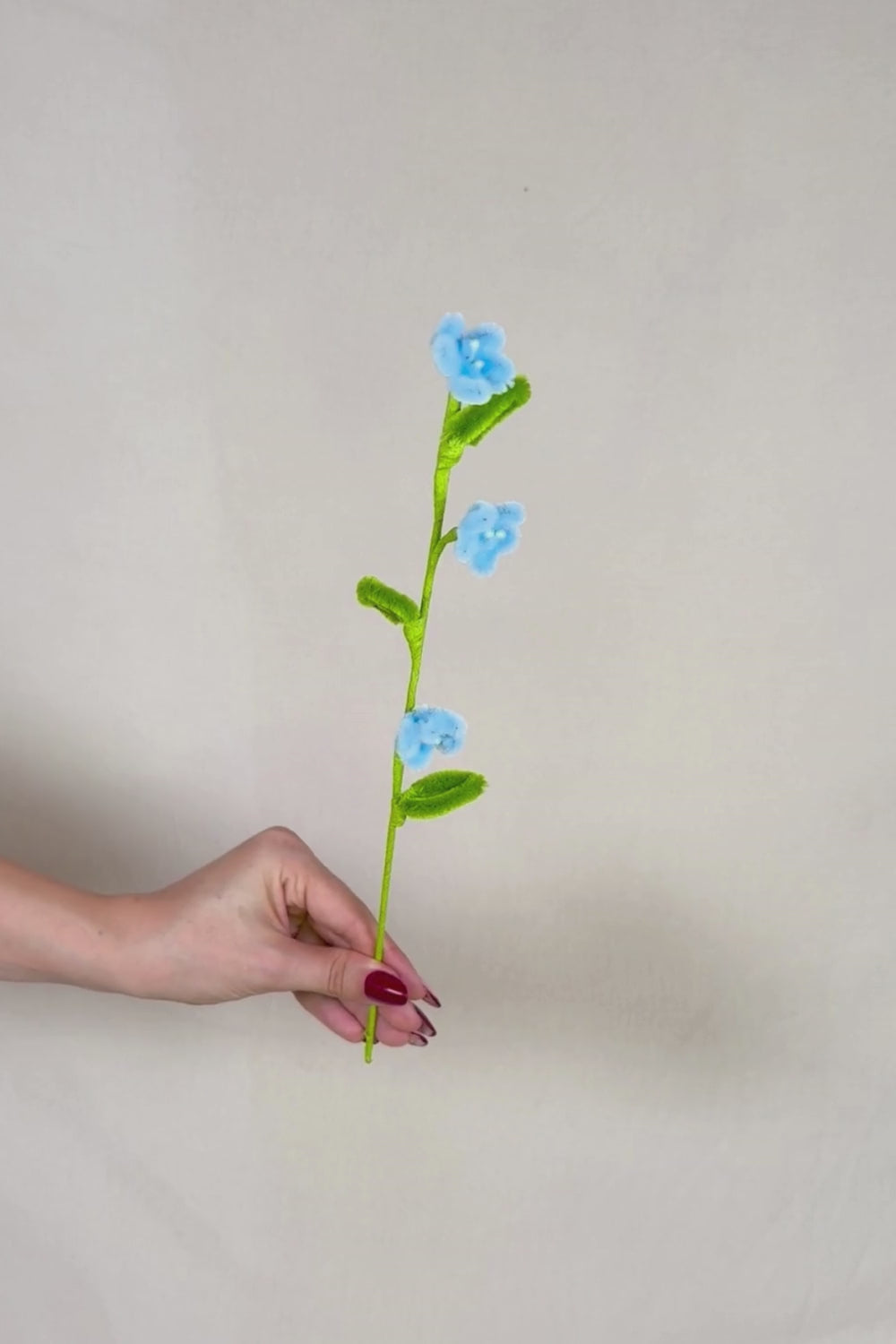 Video che fa vedere a 360 gradi un rametto con 3 mini margherite azzurre in scovolini, fatto a mano da Made By Hand in Italia, fiore artigianale decorativo 34 cm ideale per mazzi o regali floreali sostenibili